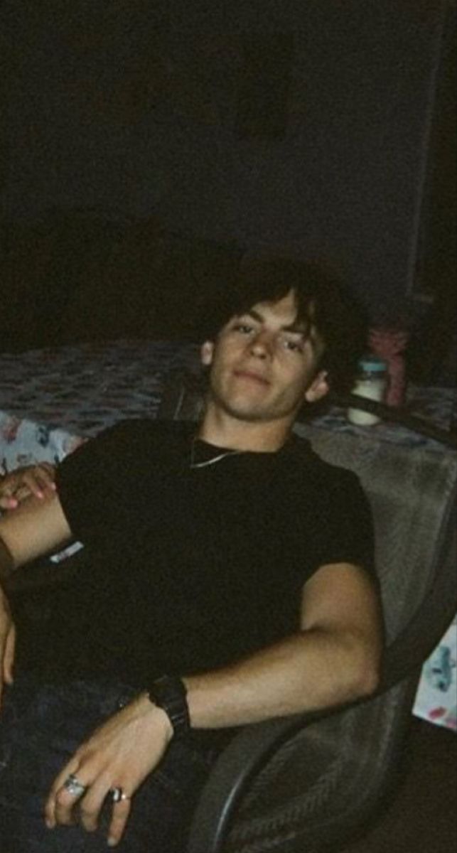 two young men sitting next to each other on a couch in a living room at night