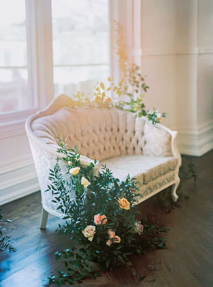 a white couch sitting on top of a hard wood floor next to a flower pot