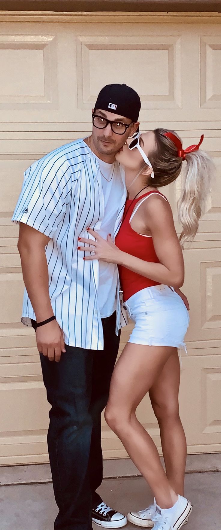 a man and woman are kissing in front of a garage door with their arms around each other