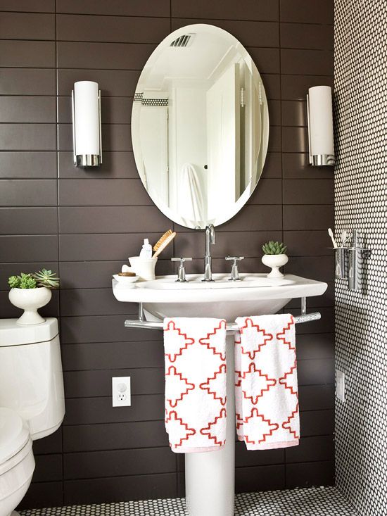 a white toilet sitting next to a sink in a bathroom under a round shaped mirror