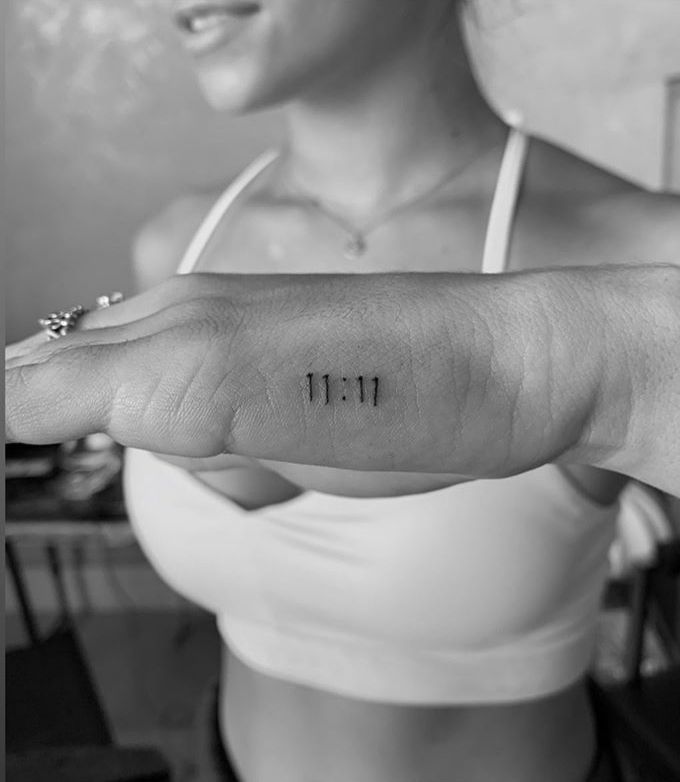 a woman with a small tattoo on her left arm that reads 11 11 and has the number thirteen