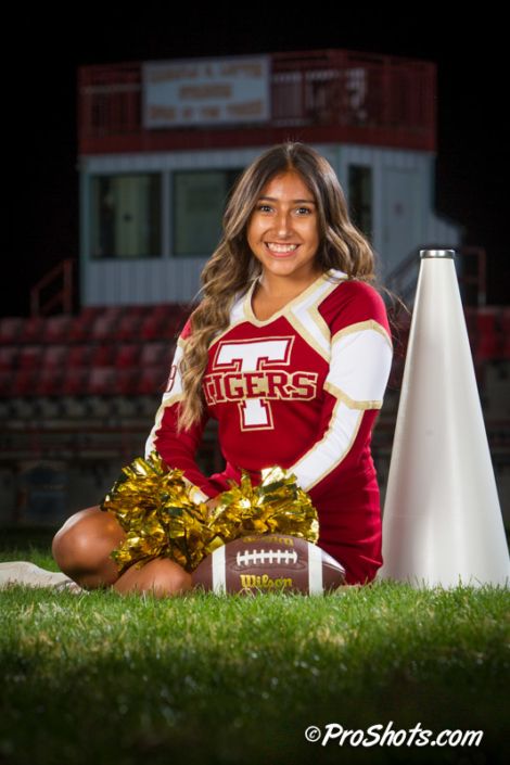 a cheerleader sitting on the ground next to a football