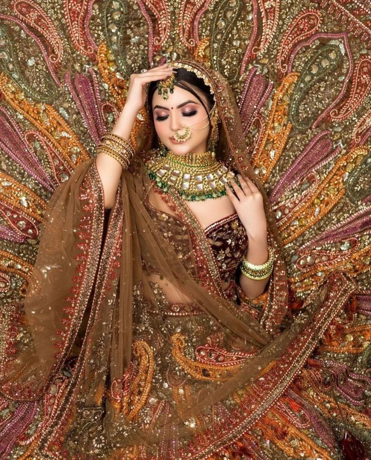 a woman in an elaborate dress with jewelry on her head and hands behind her head