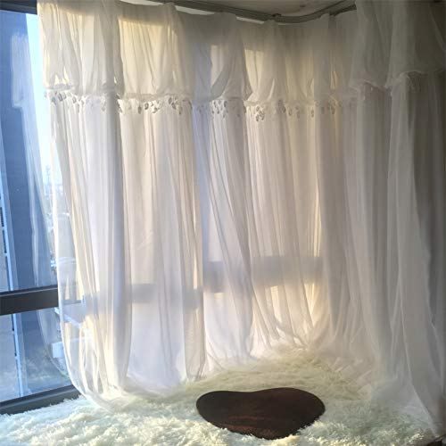 a white curtained room with a heart shaped rug on the floor