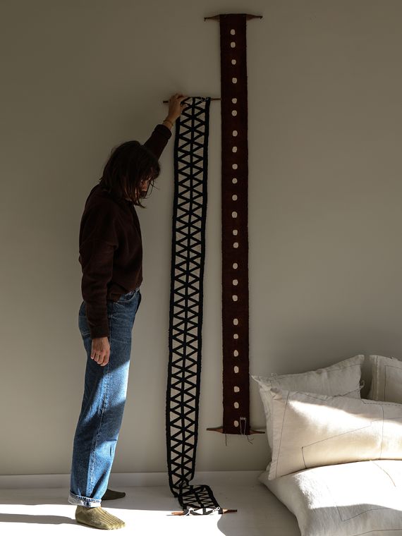 a man standing in front of a wall hanging on the side of a white wall