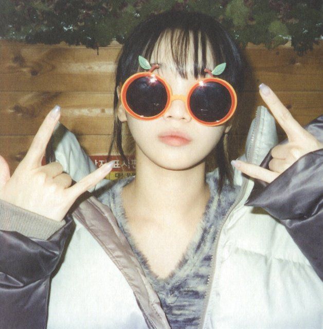 a woman wearing red sunglasses and holding up two fingers