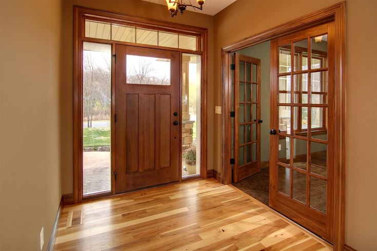 an empty room with wooden floors and double doors leading to the front door is shown