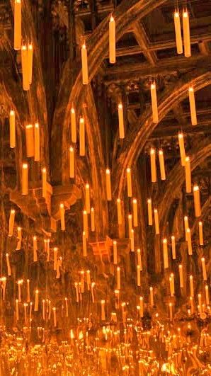 many candles are lit in the middle of a large room filled with gold colored walls