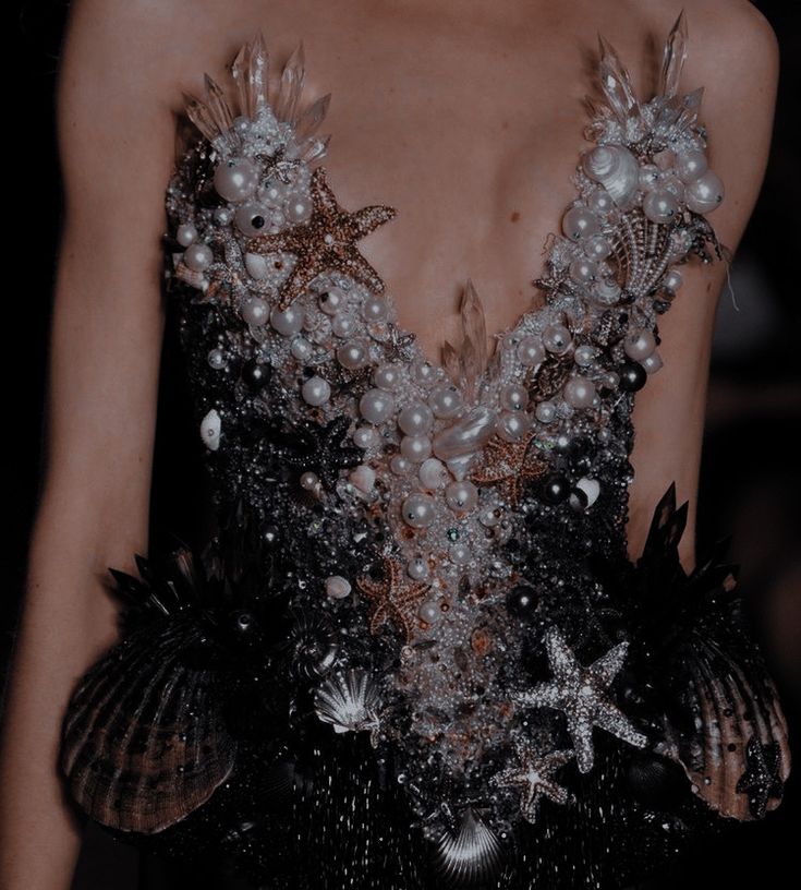 a close up of a woman's dress with pearls and seashells on it