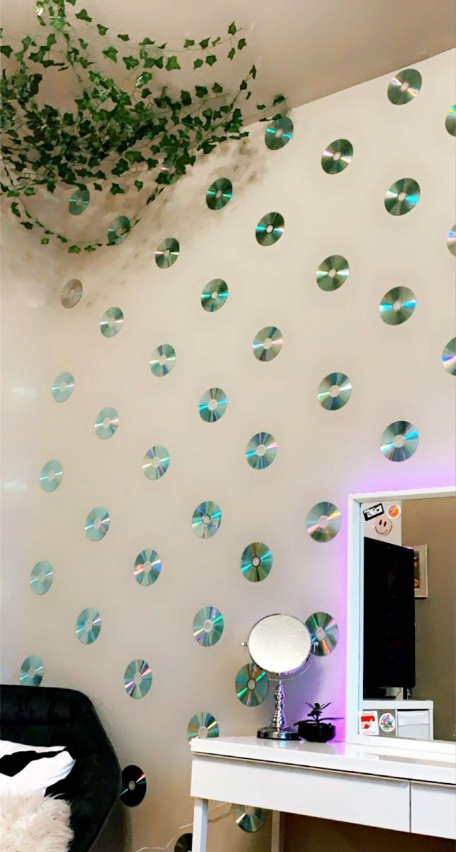 a white desk topped with a mirror next to a wall covered in green leaves and bubbles