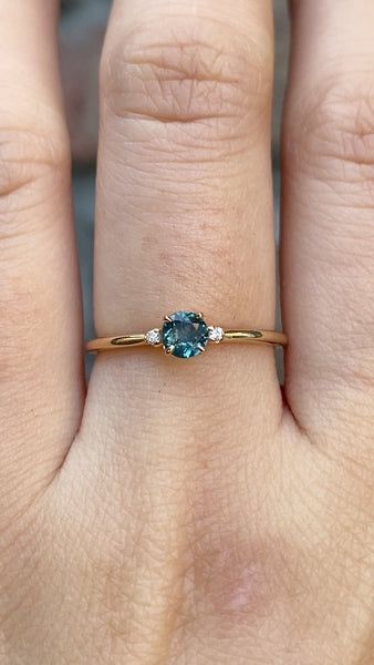 a woman's hand with a ring on it and a blue stone in the middle