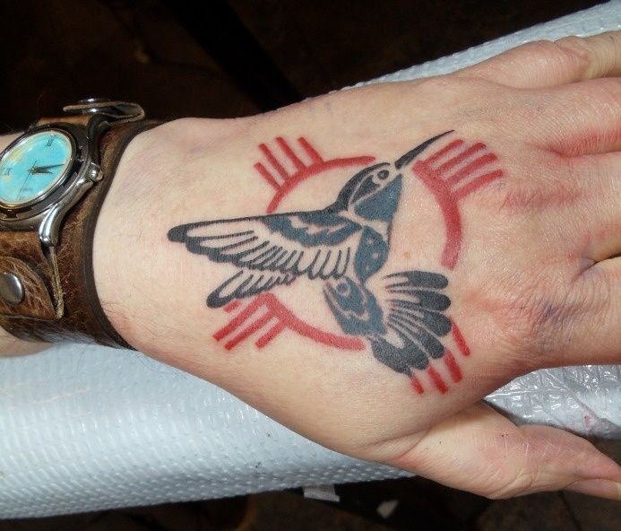 a woman's hand with a bird tattoo on it