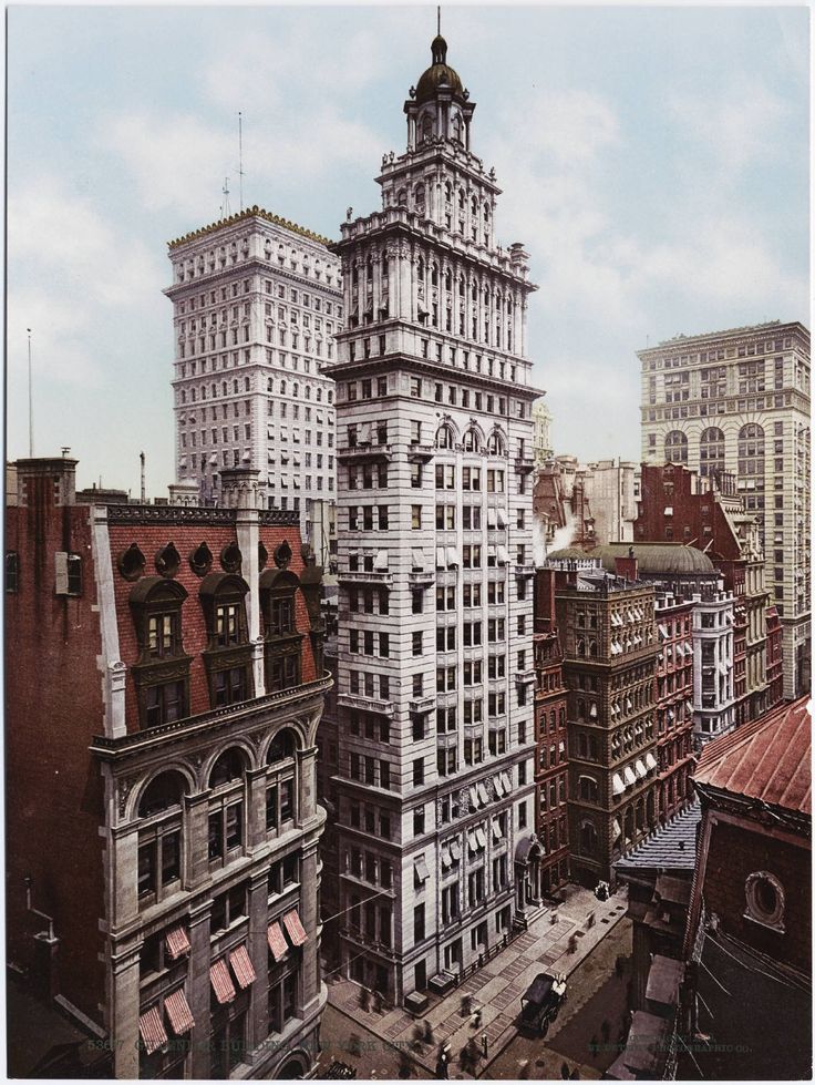 an old photo of a tall building in the middle of a city with other buildings around it