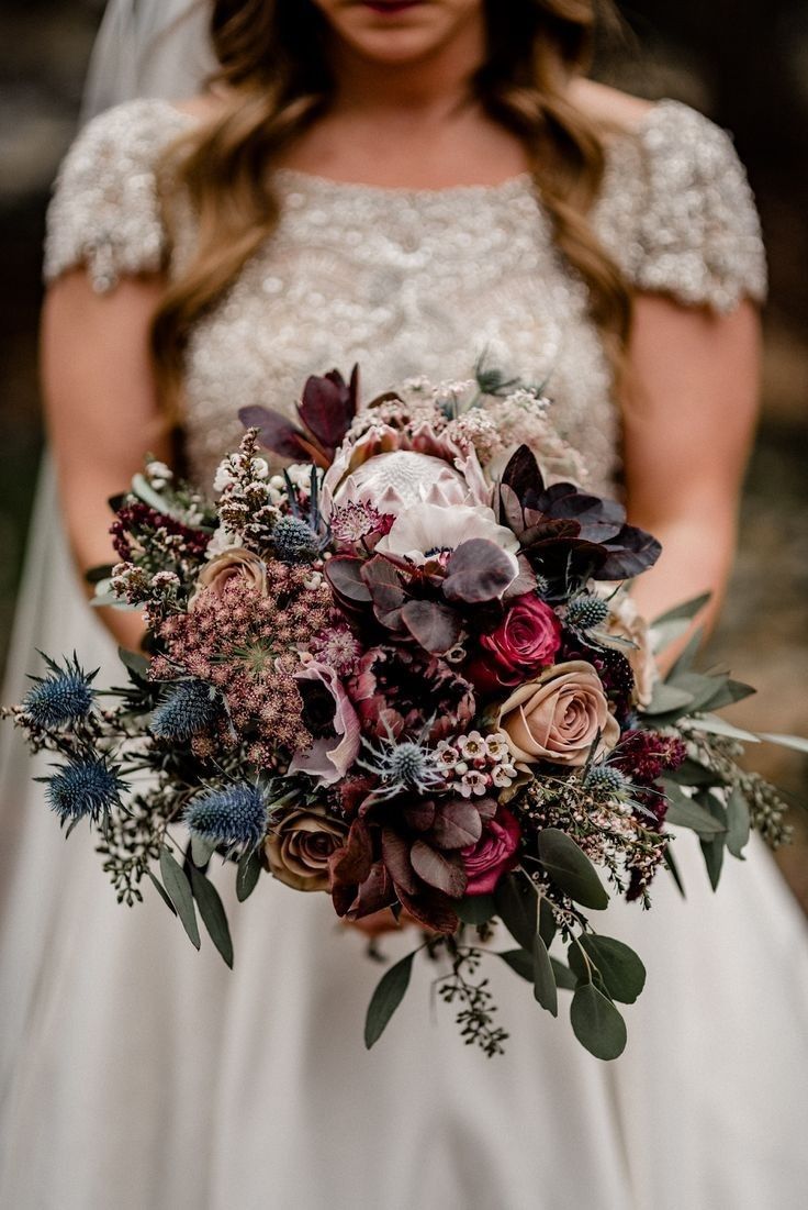 a bride holding a bouquet of flowers in her hands and looking down at the camera