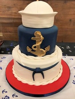 a three tiered cake decorated with an anchor and sailor's hat on top