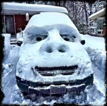 a car is covered in snow and it's head sticking out of the hood