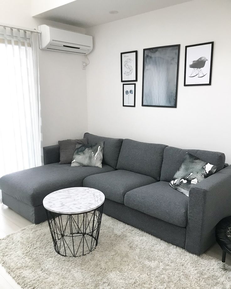 a living room with a gray couch and white rugs on the floor in front of a window