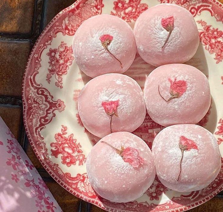 some pink donuts are on a red and white plate