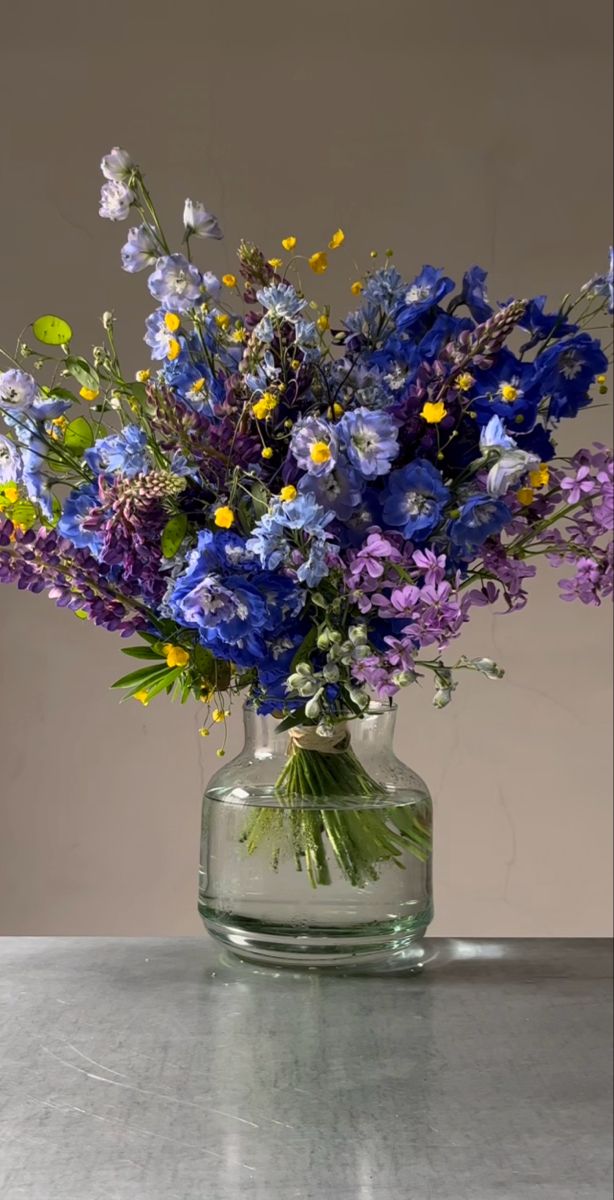 a vase filled with lots of purple and yellow flowers