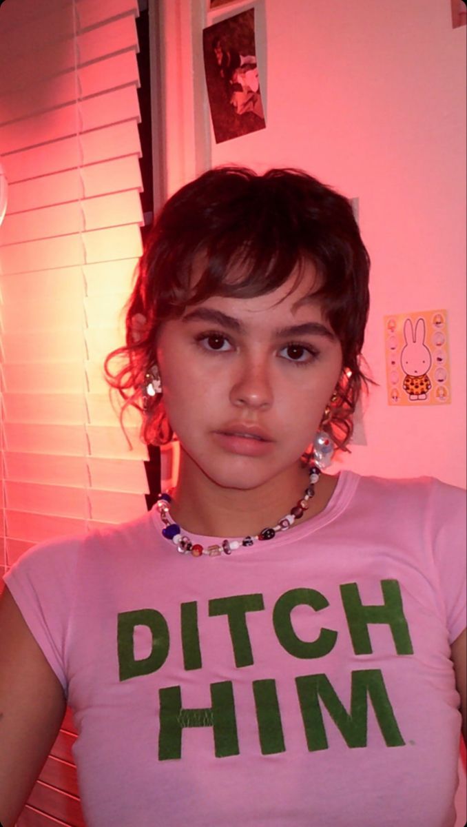 a young woman wearing a pink shirt with the word pitch him on it's chest