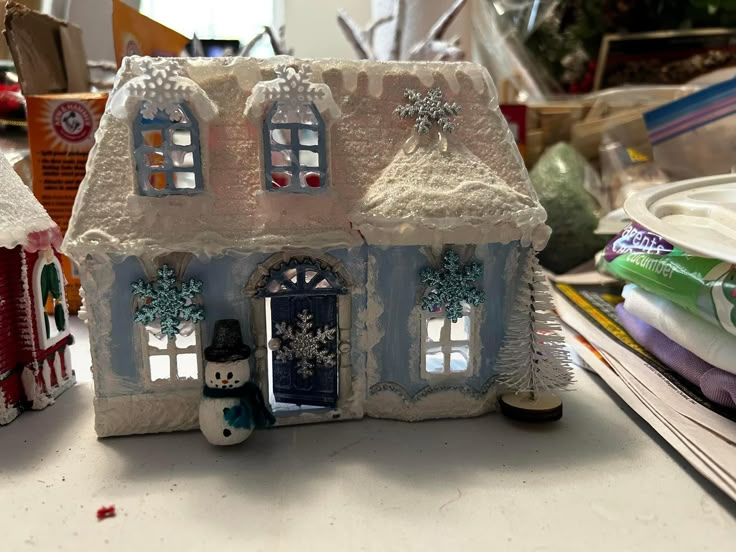 a house made out of clay sitting on top of a table next to other items