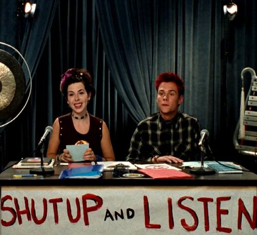 two people sitting at a table in front of microphones with the words shut and listen written on it