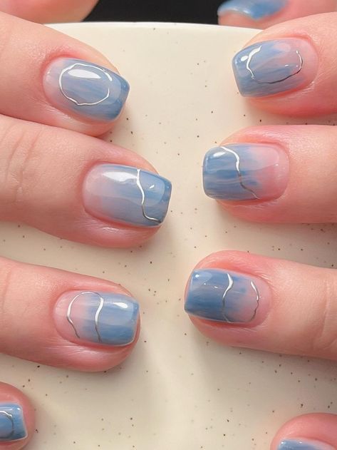 a woman's hands with blue and white nail polish on them, holding a plate