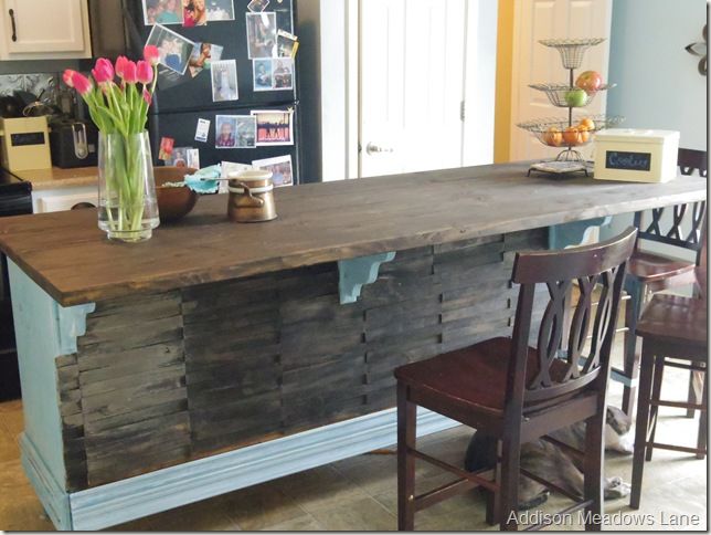 a kitchen island made out of pallet wood with flowers in a vase on top