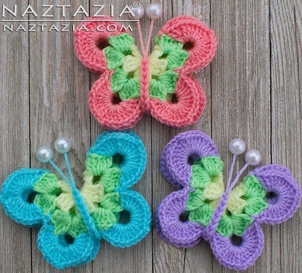 three crocheted butterflies sitting on top of a wooden table