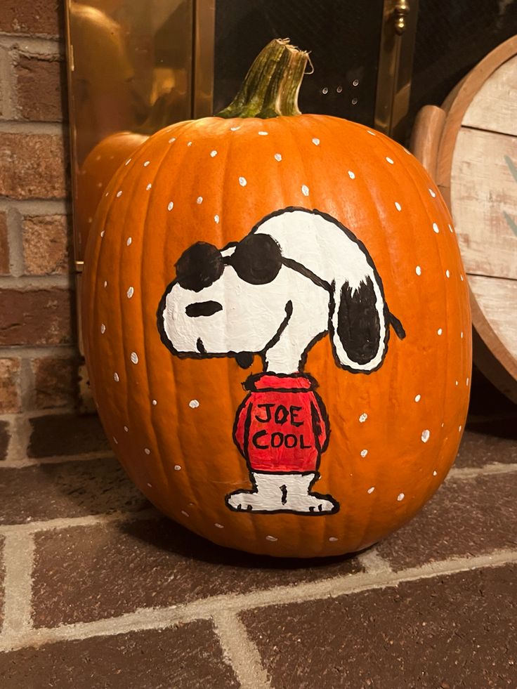 a painted pumpkin with a snoopy dog on it and the words joe cool written on it