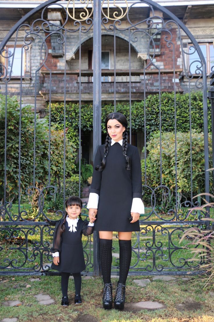 a woman and child standing in front of an iron gate