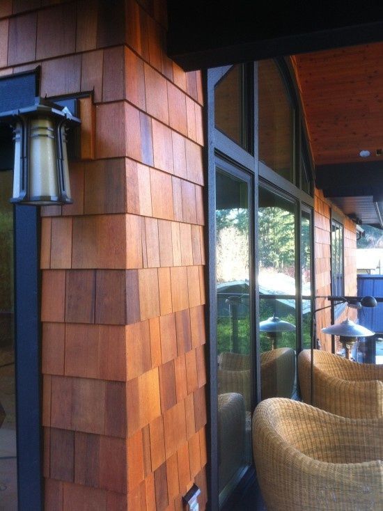 the outside of a restaurant with chairs and lamps on the side of the building that is made out of wood