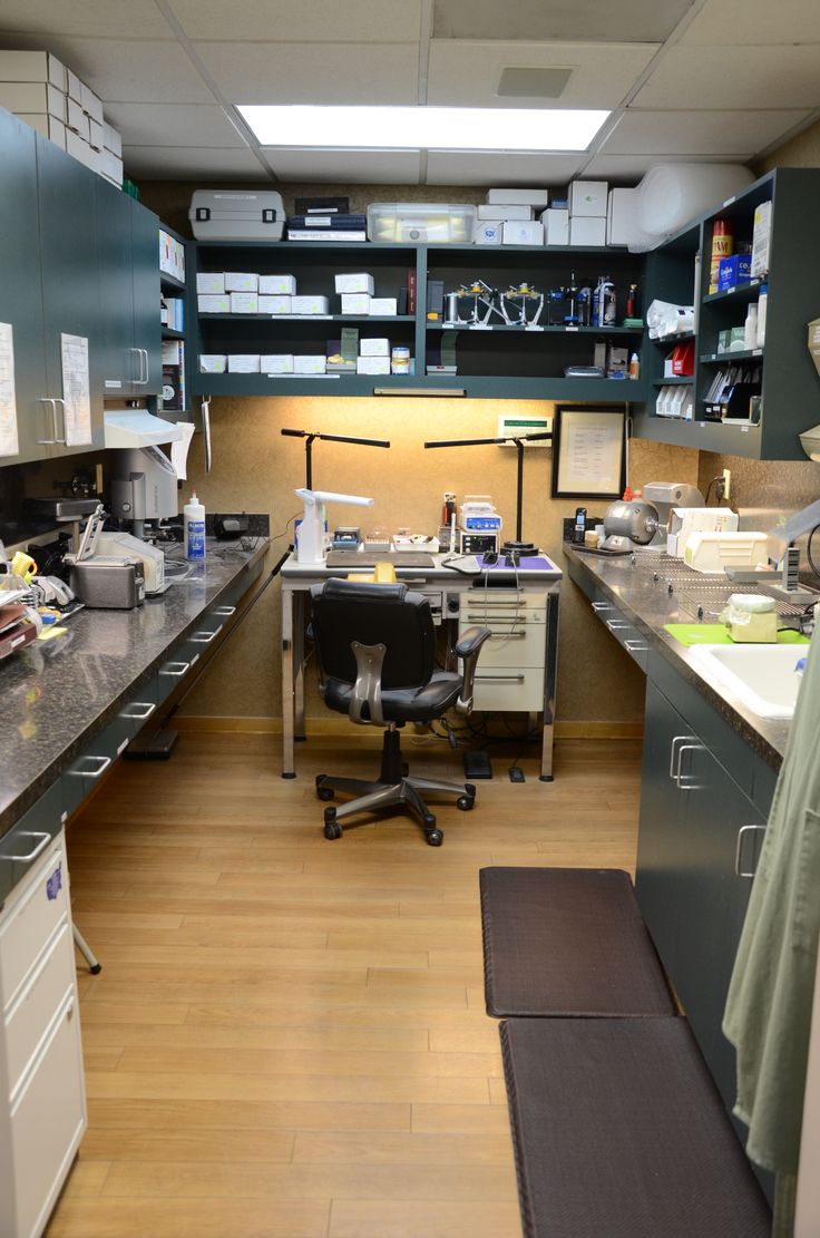 an office with many desks and shelves on the wall, along with a chair