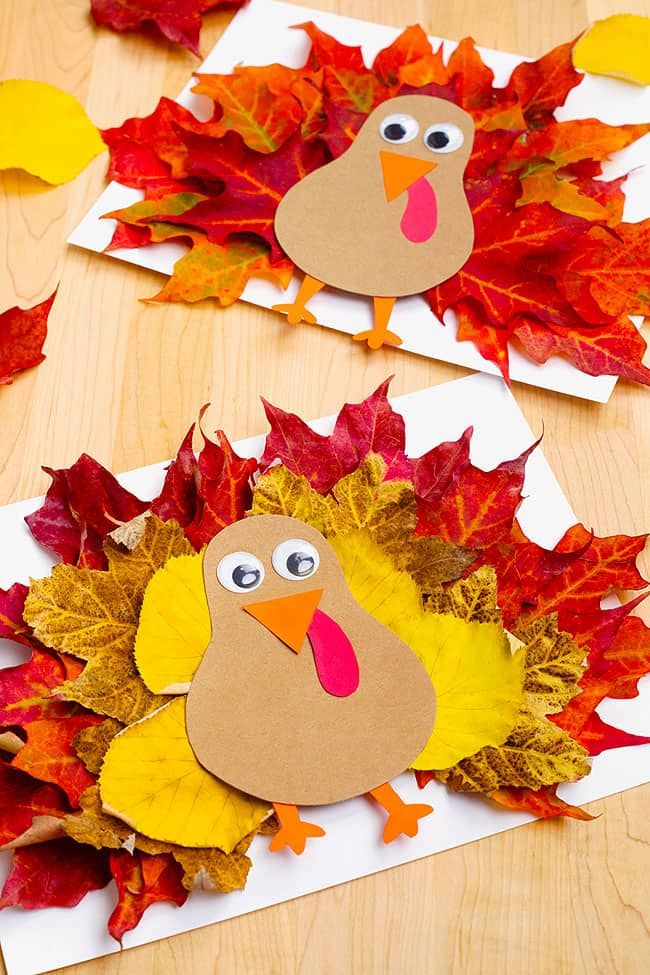 two turkeys made out of leaves on top of a wooden table next to paper plates