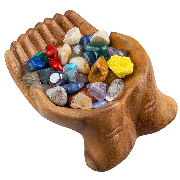 a wooden bowl filled with lots of colorful rocks and stones on top of a white background