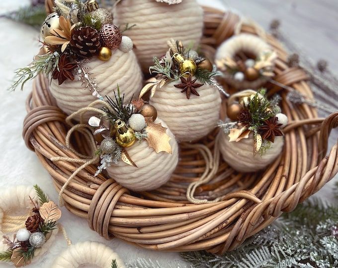 some ornaments are sitting in a wicker basket on a table next to pine cones