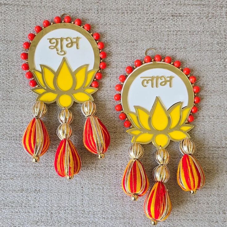 two red and yellow earrings with the word'bd'written in gold on them