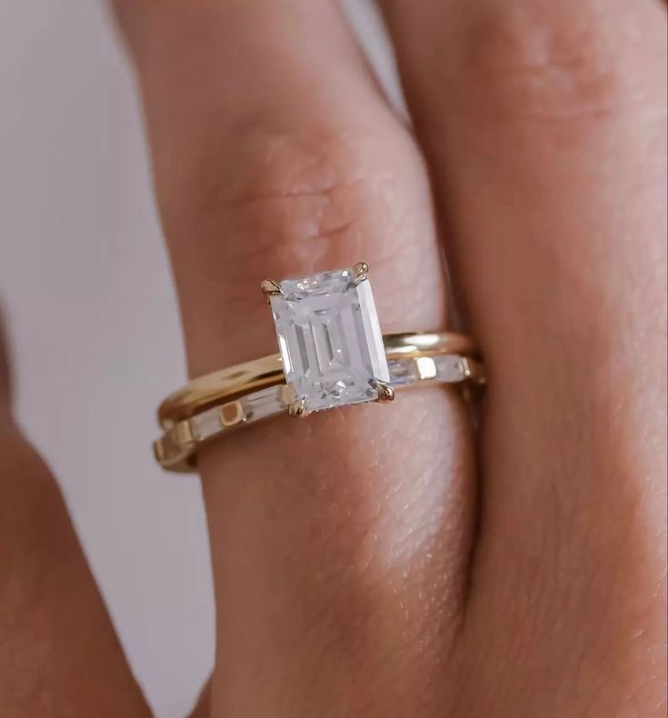 a woman's hand with a gold ring and an emerald stone