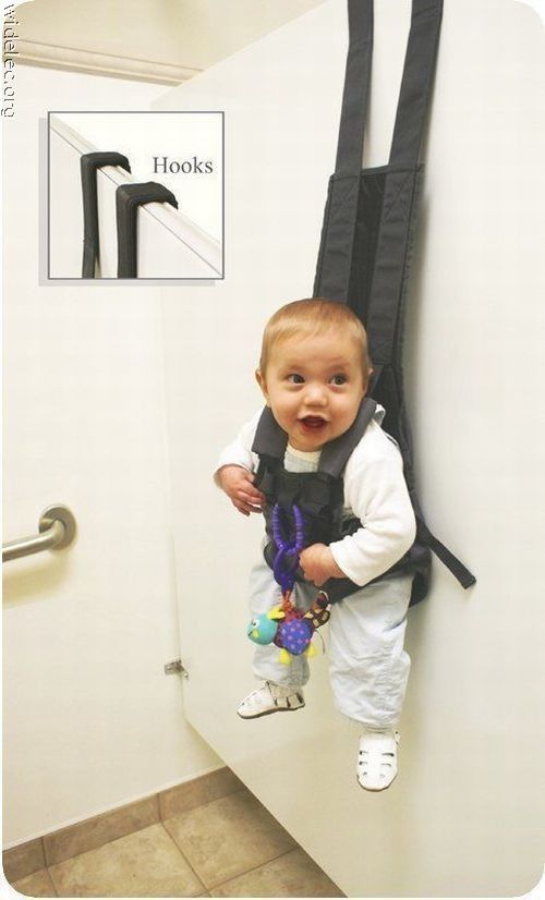 a baby standing in front of a door holding a pair of scissors