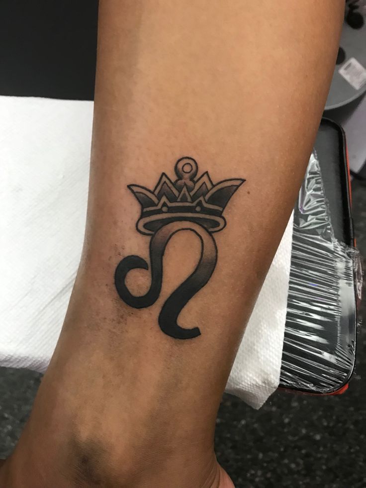 a woman's foot with a crown tattoo on her left leg and the letter s in black ink