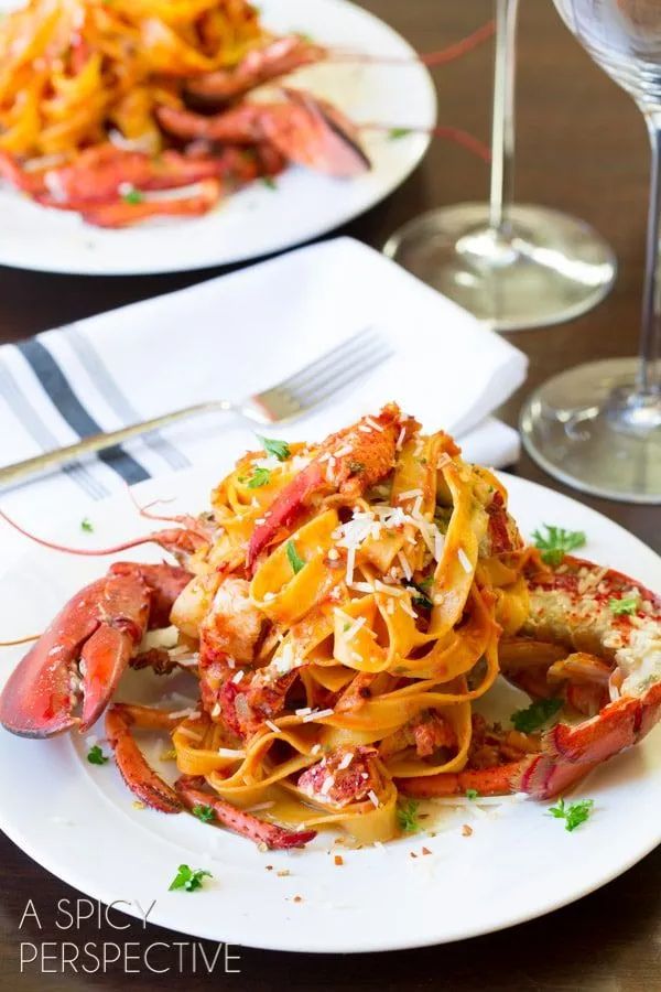 lobster and pasta dish served on plate with wine glass in the backgroung