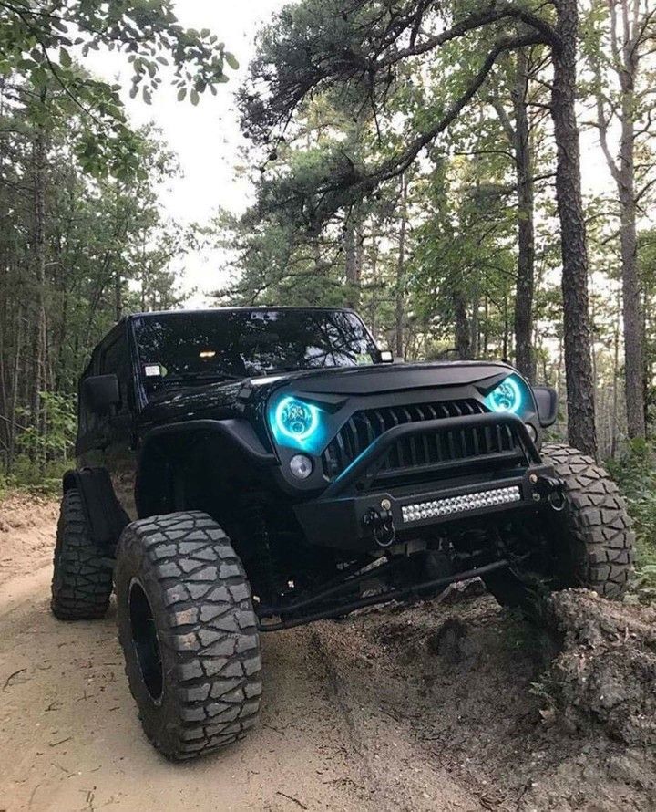 an off road vehicle with lights on driving through the woods