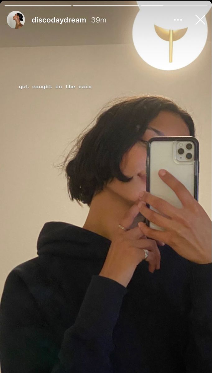 a woman taking a selfie in front of a mirror wearing a black hoodie