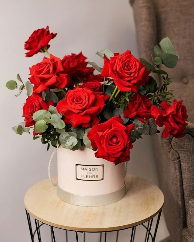 a white bucket filled with red roses sitting on top of a table next to a chair