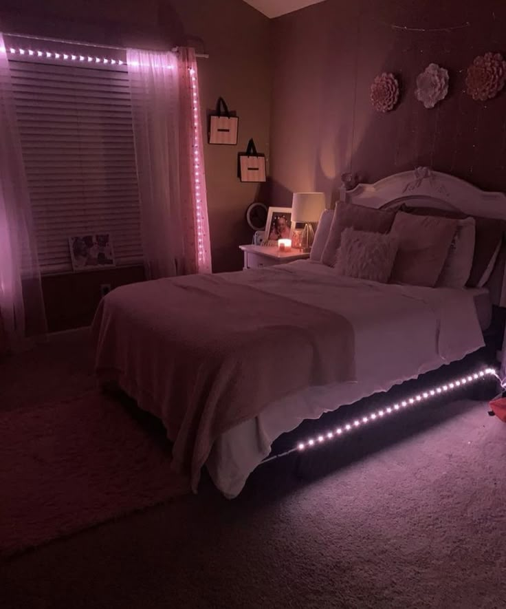 a lit up bed in a bedroom with pink lights on the headboard and foot board