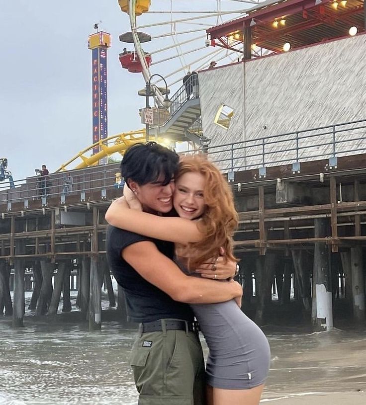 a man and woman hugging in front of a ferris wheel