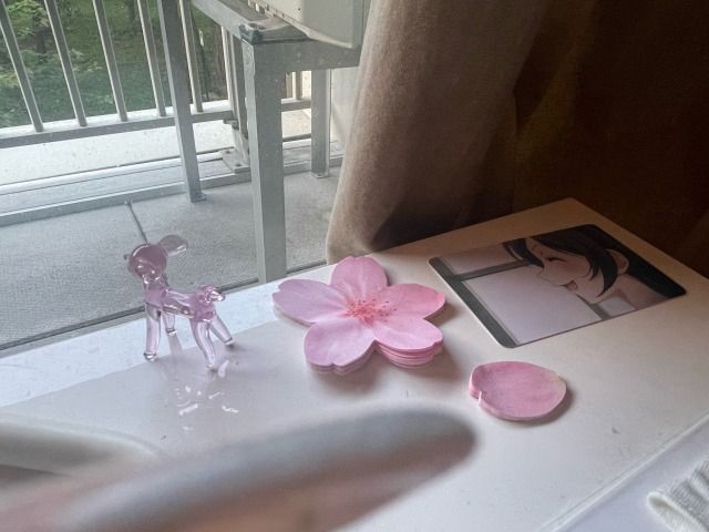 pink flowers sitting on top of a white table next to a window with a glass door