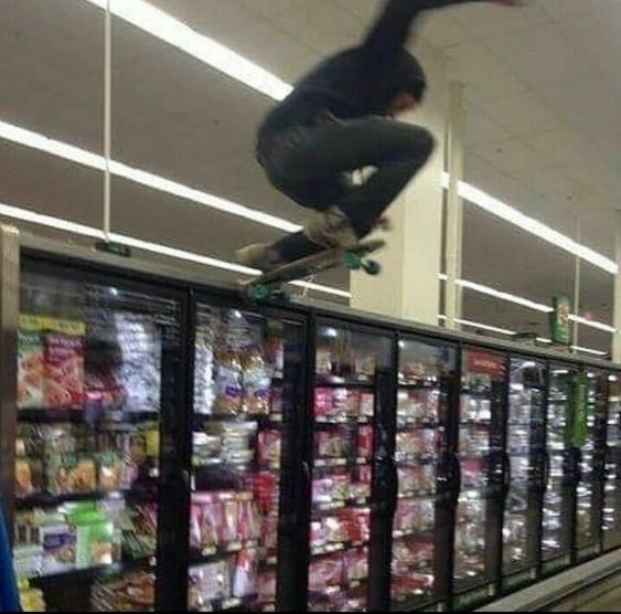 a man on a skateboard jumping over the top of a vending machine in a grocery store