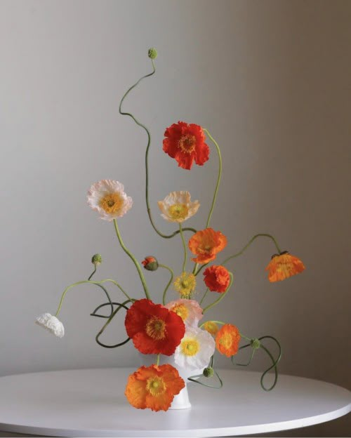 a white table topped with a vase filled with different types of flowers on top of it