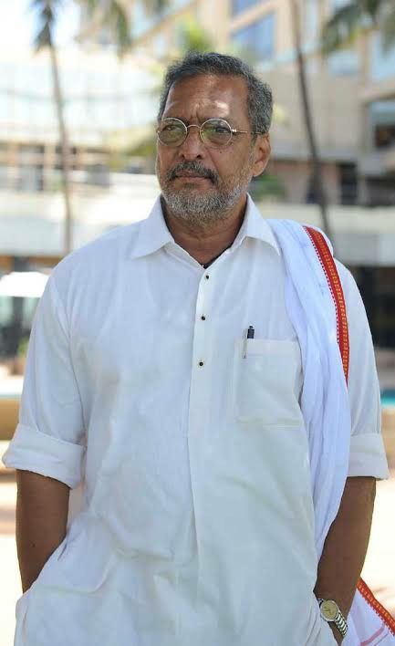 an older man with glasses and a white shirt is standing in front of a building